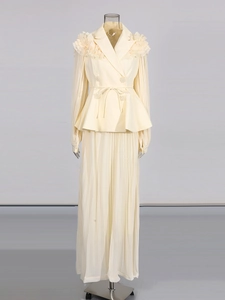 Detail of cream blazer with ruffled shoulders, pleated sleeves and matching maxi skirt