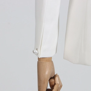 Detail of the chic white sleeve featuring a slit cuff and a large elegant pearl button