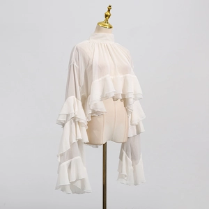 Detail of white semi-transparent chiffon top featuring tiered ruffles and high-neck design