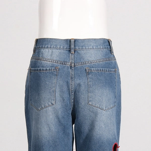Detail of high waist denim jeans featuring classic double back pockets and blue wash finish