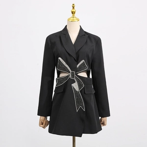 Detailed view of women's black blazer with waist cut-outs and a large rhinestone bow