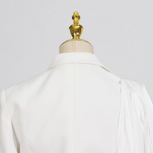 Detail of white tailored blazer collar and shoulder drape on a beige mannequin stand