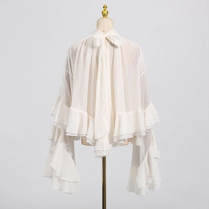 Detail view of the back of a white mesh blouse with ruffled hem and bow collar design