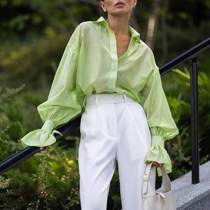 Detail of light green sheer blouse with puff sleeves and ruffled cuffs in natural light