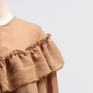 Detail of ruffled mesh stitching and tiered sleeve design on stylish brown blouse