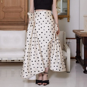Détail de la jupe à pois à taille haute avec plis latéraux et un nœud décoratif chic