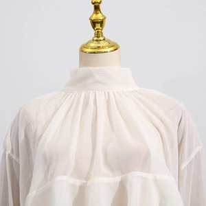 Close-up of elegant pleated high collar design on white mesh long sleeve blouse