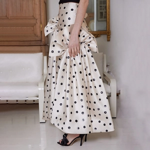 Détail d'une jupe beige à pois noirs, taille haute avec un grand nœud décoratif