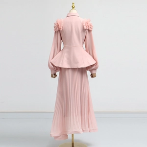 Detail of pink suit set featuring 3D floral shoulder ornaments and pleated peplum waist