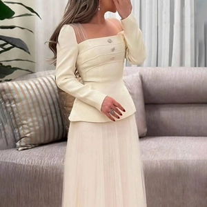 Detail of square neckline with sheer mesh paneling and rhinestone buttons on beige top