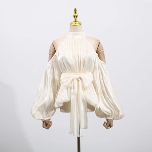 Detail of elegant off-shoulder ivory blouse with lantern sleeves and a large bow tie