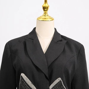 Close-up of sparkling rhinestone bow detail on a black slim-fit cropped blazer