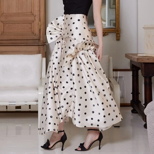 Détail d'une jupe mi-longue à pois taille haute avec volants asymétriques et nœud
