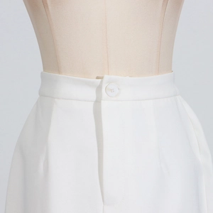 Detailed view of the white skirt waistline with button closure and fine pleated tailoring