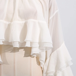 Detail of elegant white sheer mesh blouse showing ruffled tiers and delicate fabric texture