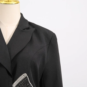 Macro view of crystal bow embellishment on the black slim fit blazer for women