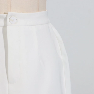 Detail shot of white skirt waist featuring a round button and side pocket design