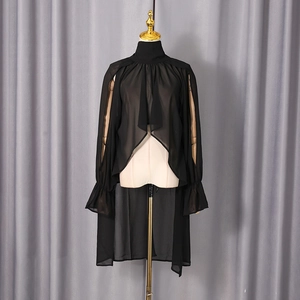 Detail of high neck black sheer top with ruffled cuffs and asymmetric layered hem
