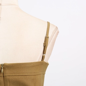 Detail of adjustable strap with silver buckle and invisible zipper on olive green jumpsuit