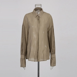 Detail showing sheer khaki long sleeve shirt fabric with standard collar and button cuff
