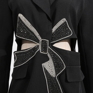 Close-up of sparkling black and silver rhinestone bow detail on a cutout blazer jacket