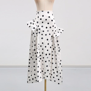 Détail d'une jupe longue blanche à taille haute avec gros pois noirs et volants latéraux