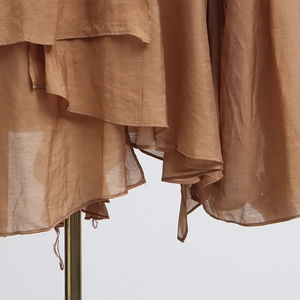 Detail shot of layered ruffle mesh design and pleated fabric texture on a brown blouse