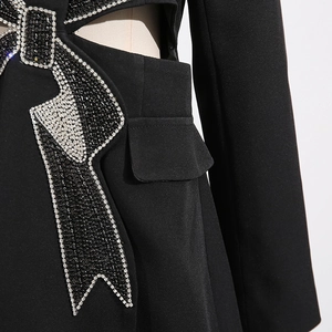 Detailed close-up of bow pattern with rhinestones and waist cutout on black blazer