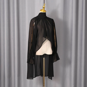 Detail of sheer black chiffon top featuring high neck and asymmetric hi-lo hemline