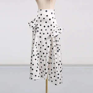 Détail d'une jupe midi blanche à pois noirs avec des volants asymétriques superposés