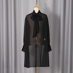 Detail of sheer black blouse featuring a large bow neckline and ruffled bell sleeves