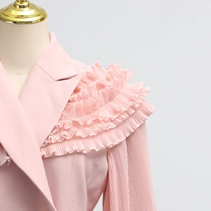 Detail of light pink blazer featuring layered ruffle shoulders and vertical pleated sleeves
