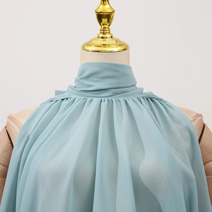Close-up of light blue chiffon halter top featuring a ruffled high-neck on a mannequin