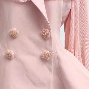 Detail of pink pleated sleeves and handcrafted beaded ball buttons on a summer outfit