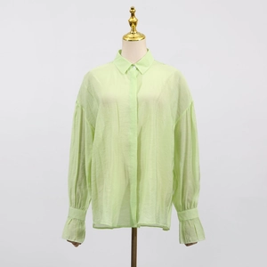 Detail showing the light green blouse with ruffled cuffs and textured breathable fabric