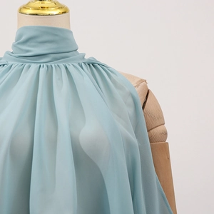 Detail of light blue sleeveless chiffon top with pleated high neck on wooden mannequin