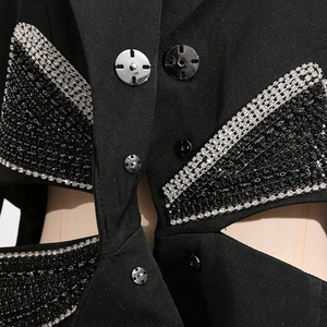 Macro detail of silver rhinestone bow and cutout on black fitted suit jacket