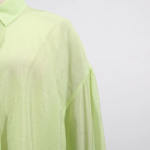 Detailed view of light green pleated blouse with elegant puff long sleeves and turn-down collar