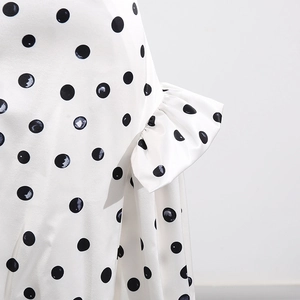 Détail du motif à pois noirs et du design drapé sur le tissu de la jupe blanche
