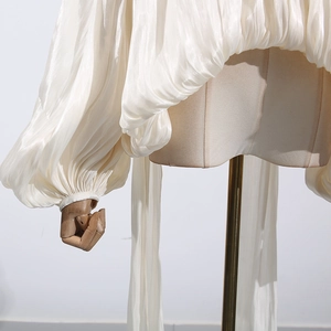 Detail of white pleated puff sleeves made from glossy translucent silk-like fabric