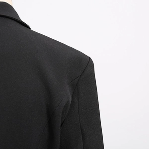 Close-up of the shoulder detail on a black tailored blazer with padded structure