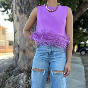 Detailed close-up of purple sleeveless top featuring premium ostrich feather trim hem