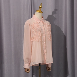 Detailed view of peach chiffon shirt featuring layered ruffles and classic white buttons