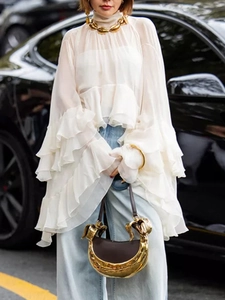 Elegant white mesh ruffled blouse paired with high-waist jeans and gold shell jewelry