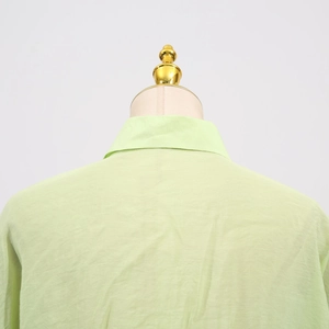 Detail of light green casual shirt back featuring turn-down collar and textured fabric
