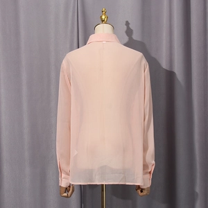 Detail view of pink chiffon blouse fabric texture and neat stitching on back panel