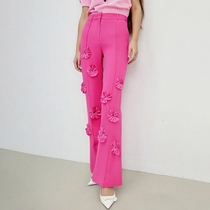 Dettaglio dei fiori in tessuto 3D sui pantaloni a zampa rosa a vita alta