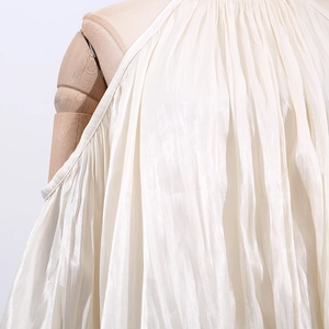 Detailed macro view of ivory pleated halter neck top with premium silk-like texture