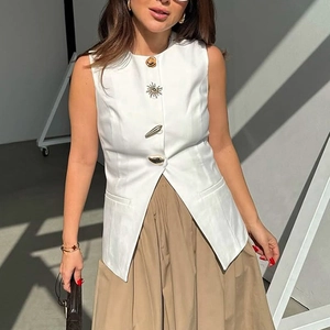 Detail of white sleeveless vest with unique sun-shaped metal buttons and irregular hem