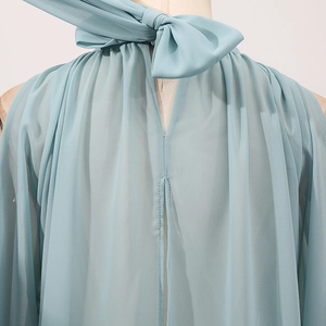 Detail of light blue sleeveless chiffon top with bow tie neck and soft pleated texture